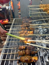 Dabbing oil with lemongrass on satay on the BBQ